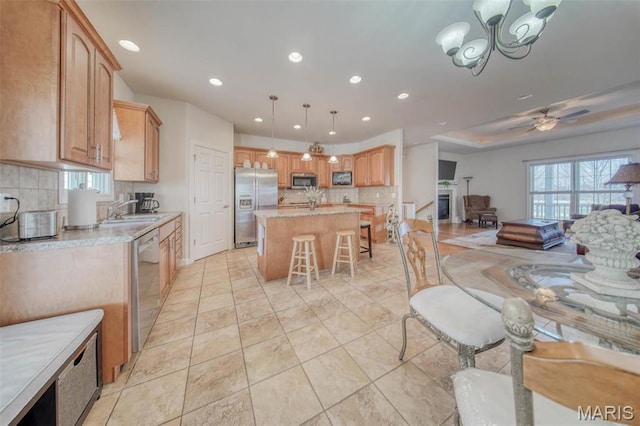 17205 Elk Prairie Dr, Rolla, MO 65401 - kitchen featuring appliances with stainless steel finishes, backsplash, light countertops, a kitchen bar, and a kitchen island with sink
