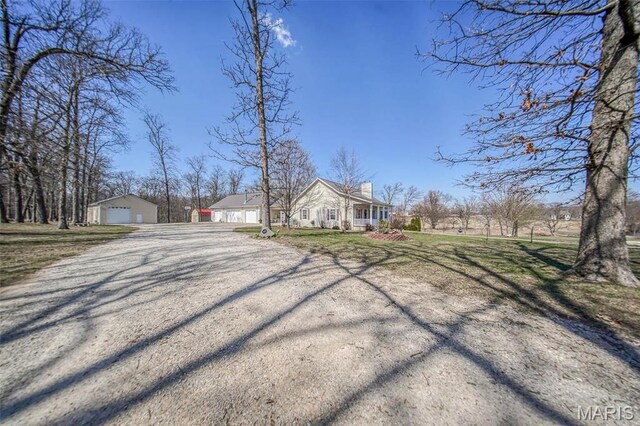 17205 Elk Prairie Dr, Rolla, MO 65401 - view of front of house with a detached garage, a chimney, an outbuilding, gravel driveway, and a front lawn