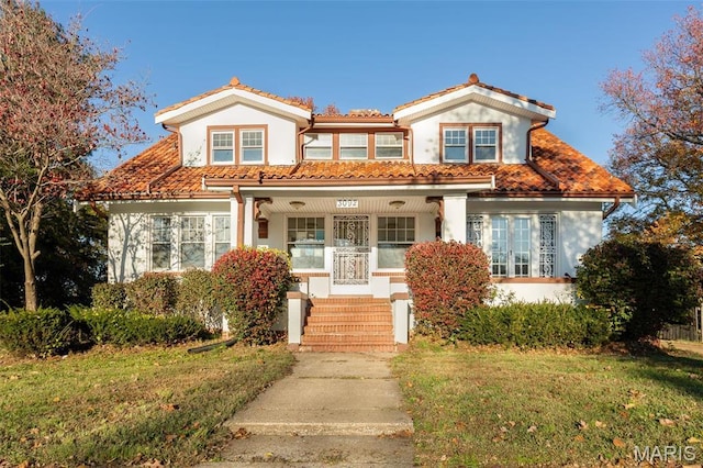 3092 Bellerive Dr, Saint Louis, MO 63121 - mediterranean / spanish house with stucco siding, a front yard, a tile roof, and covered porch