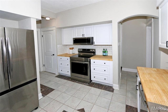 3092 Bellerive Dr, Saint Louis, MO 63121 - kitchen featuring stainless steel appliances, wood counters, arched walkways, tasteful backsplash, and light tile patterned flooring