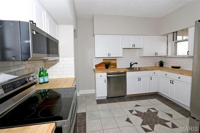 3092 Bellerive Dr, Saint Louis, MO 63121 - kitchen with wooden counters, stainless steel appliances, a sink, white cabinetry, and light tile patterned floors
