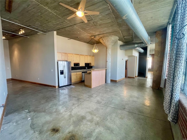 kitchen with light brown cabinetry, open floor plan, stainless steel fridge, concrete floors, and baseboards