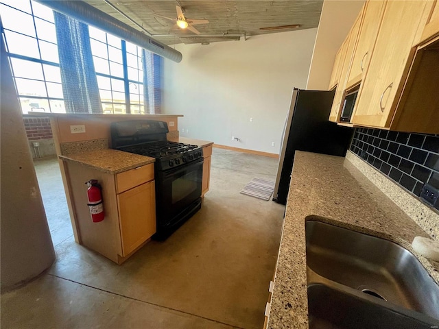 kitchen with black gas range, backsplash, a sink, and light brown cabinets