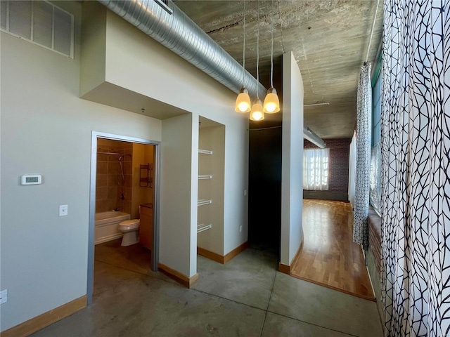 hallway featuring baseboards and concrete floors