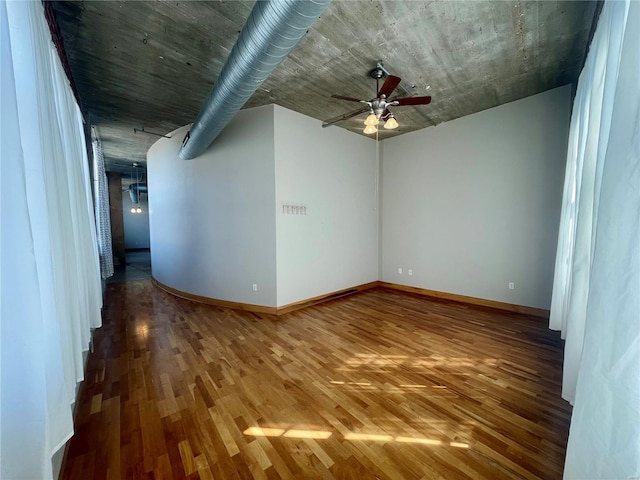 empty room featuring ceiling fan, wood finished floors, and baseboards