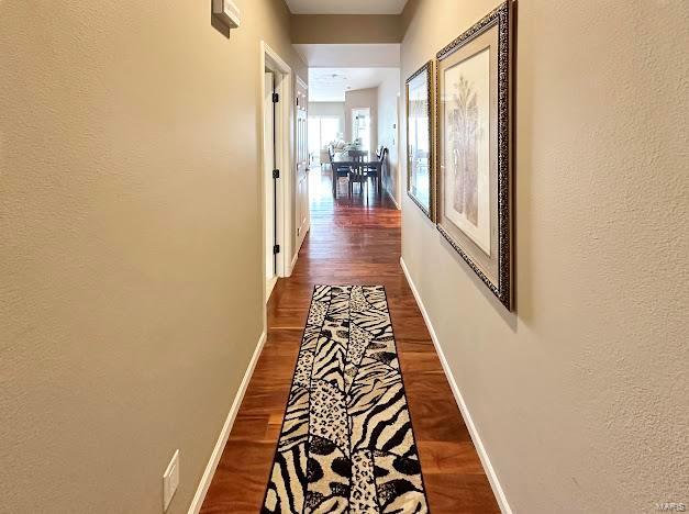 hallway with dark wood finished floors and baseboards