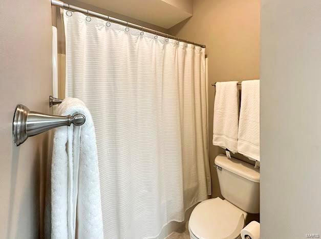 full bath featuring toilet and curtained shower