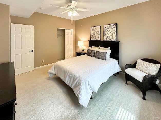 bedroom featuring light carpet, a closet, baseboards, and ceiling fan