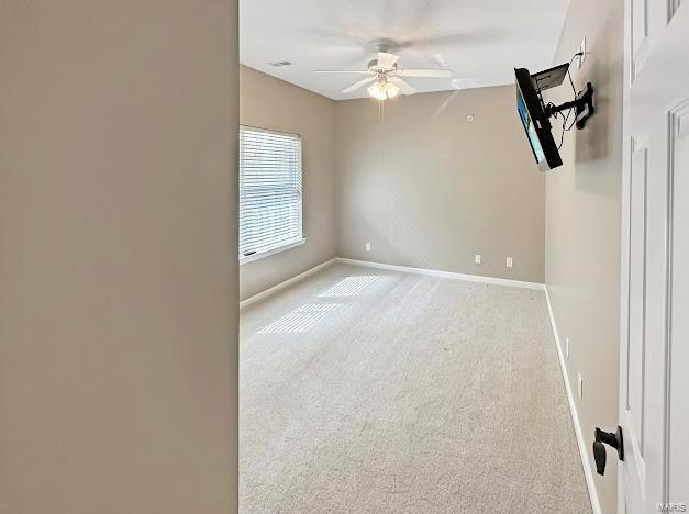 carpeted spare room featuring ceiling fan and baseboards