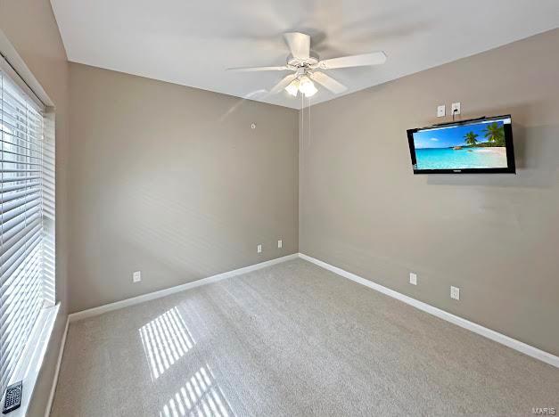 carpeted empty room with a ceiling fan and baseboards