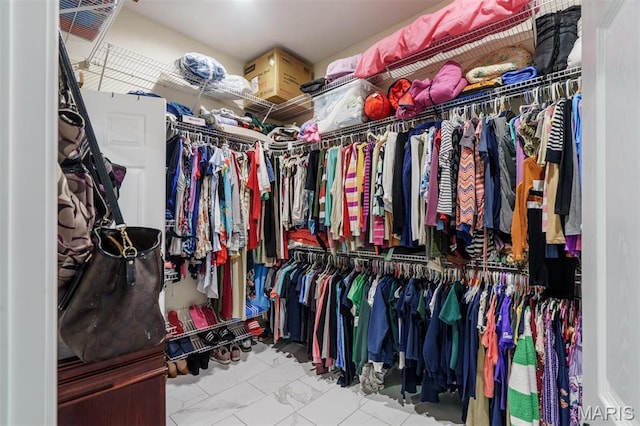 walk in closet featuring marble look tiles