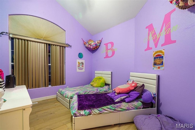 bedroom with lofted ceiling and light wood finished floors