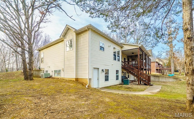 view of side of home featuring stairs, a ceiling fan, a wooden deck, central air condition unit, and a yard