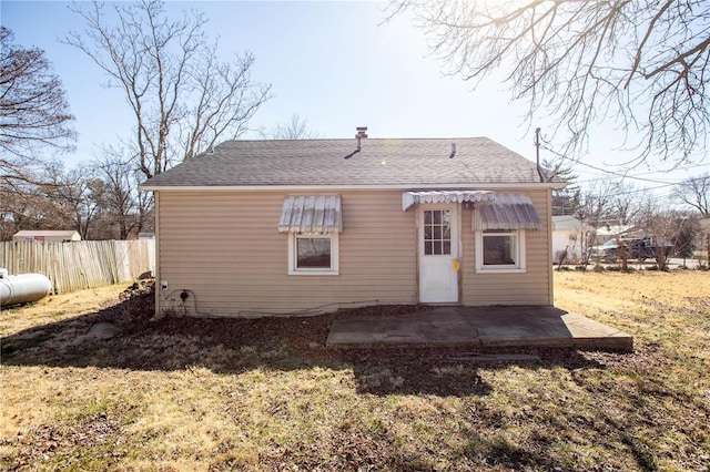 back of property with fence, a patio area, and roof with shingles