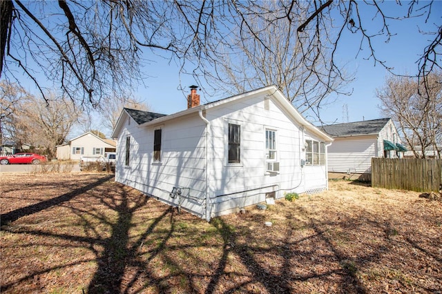 view of property exterior with a chimney, fence, and cooling unit
