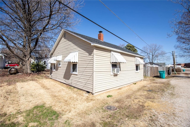 view of side of home with a chimney and cooling unit