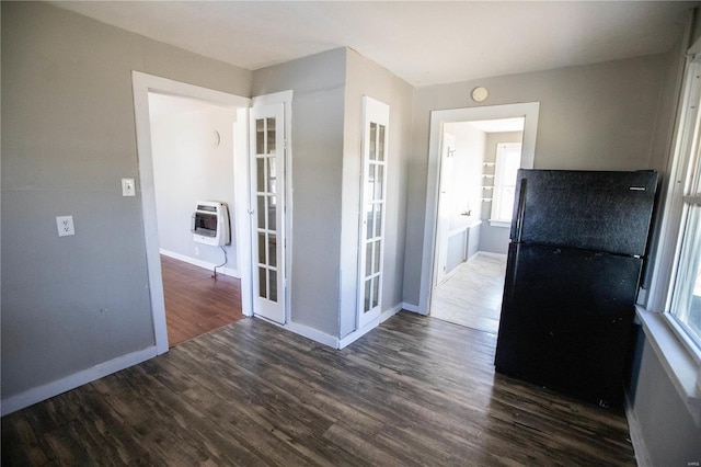 spare room featuring heating unit, wood finished floors, baseboards, and plenty of natural light