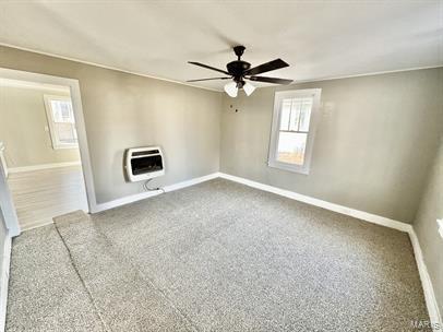 carpeted empty room with heating unit, a ceiling fan, plenty of natural light, and baseboards