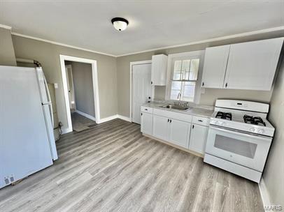 kitchen featuring white appliances, a sink, white cabinets, light wood-type flooring, and light countertops