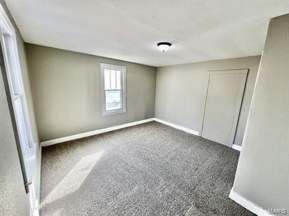 unfurnished room featuring carpet and baseboards