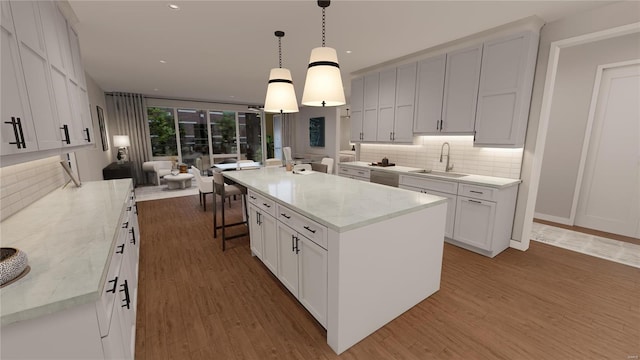 kitchen with a sink, decorative backsplash, wood finished floors, white cabinetry, and light stone countertops
