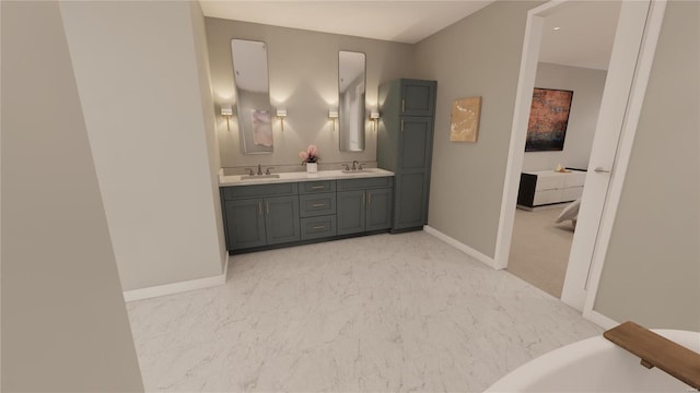 full bath with marble finish floors, baseboards, double vanity, and a tub to relax in