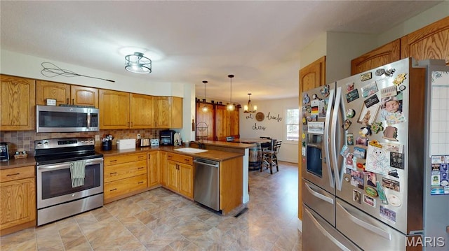 20 Denzel Dr, Greenville, IL 62246 - kitchen with stainless steel appliances, a peninsula, decorative backsplash, hanging light fixtures, and brown cabinets