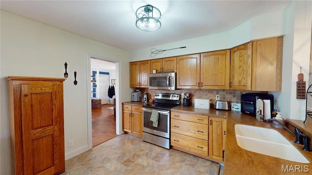 20 Denzel Dr, Greenville, IL 62246 - kitchen featuring appliances with stainless steel finishes, a sink, decorative backsplash, and baseboards