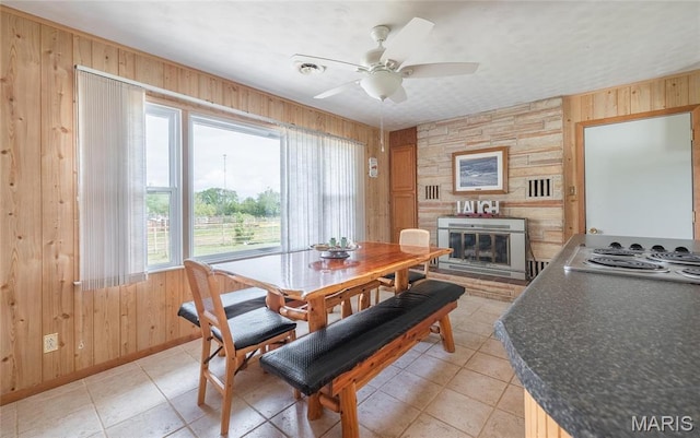 24265 Vinyard Rd, Cuba, MO 65453 - dining space featuring wooden walls, a large fireplace, ceiling fan, light tile patterned flooring, and baseboards