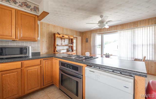 24265 Vinyard Rd, Cuba, MO 65453 - kitchen featuring stainless steel appliances, a peninsula, wooden walls, a ceiling fan, and dark countertops