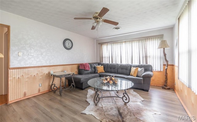 24265 Vinyard Rd, Cuba, MO 65453 - living room featuring plenty of natural light, wainscoting, wood finished floors, a ceiling fan, and wood walls