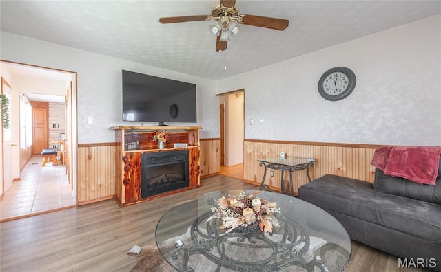 24265 Vinyard Rd, Cuba, MO 65453 - living area with wainscoting, wood finished floors, ceiling fan, wooden walls, and a fireplace