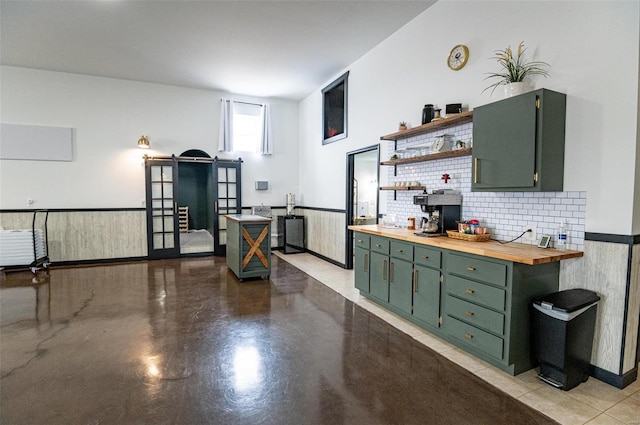 kitchen featuring green cabinetry, butcher block countertops, open shelves, concrete floors, and wainscoting