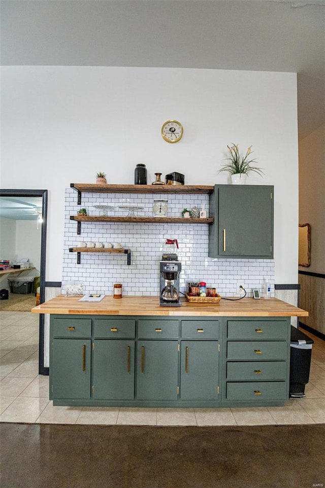 kitchen featuring green cabinetry, open shelves, wooden counters, light tile patterned flooring, and decorative backsplash