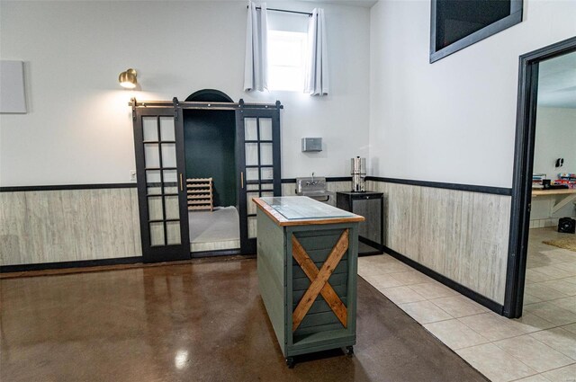 interior space with a barn door, a wainscoted wall, finished concrete floors, and wooden walls