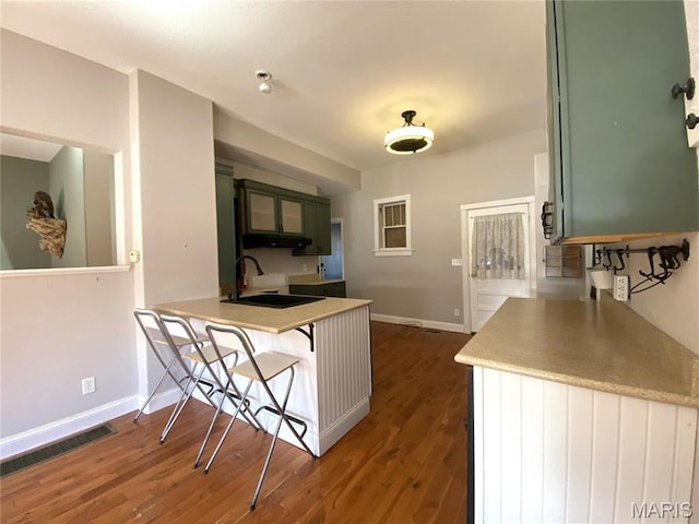209 E 3rd St, Hermann, MO 65041 - kitchen featuring a sink, baseboards, a kitchen breakfast bar, dark wood-style floors, and a peninsula