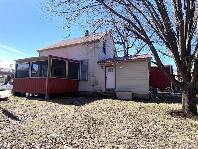 209 E 3rd St, Hermann, MO 65041 - view of front of house featuring a sunroom, entry steps, metal roof, and a chimney