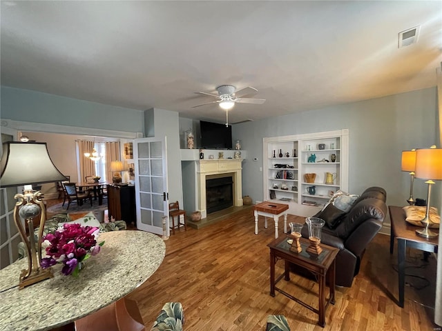 506 E Jefferson St, Perry, MO 63462 - living area featuring ceiling fan, a fireplace with raised hearth, wood finished floors, and a chandelier