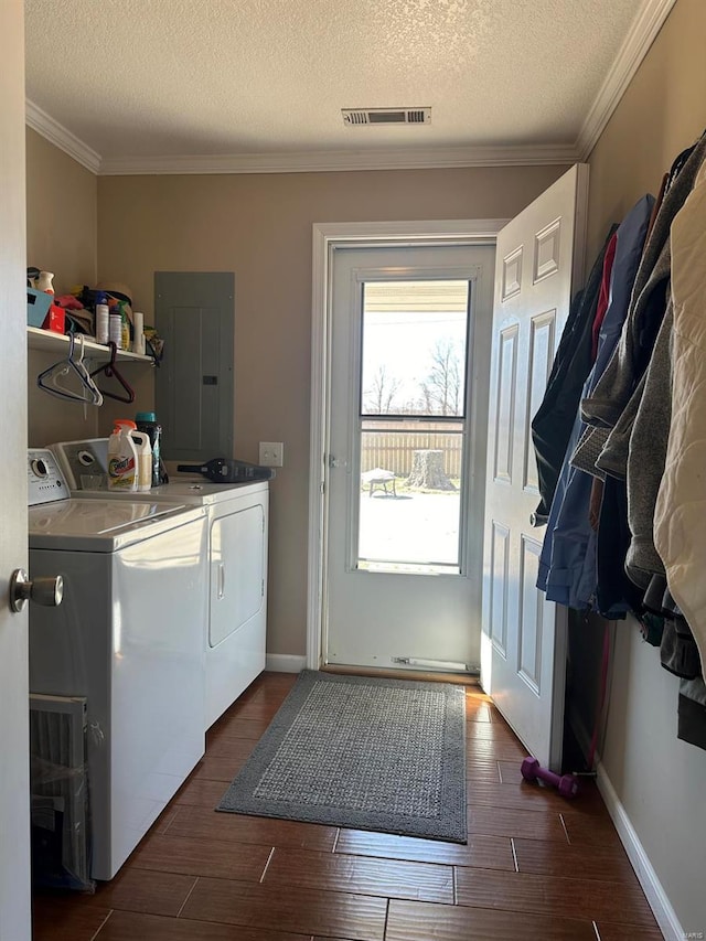 laundry room featuring electric panel, washing machine and clothes dryer, a textured ceiling, ornamental molding, and dark wood finished floors