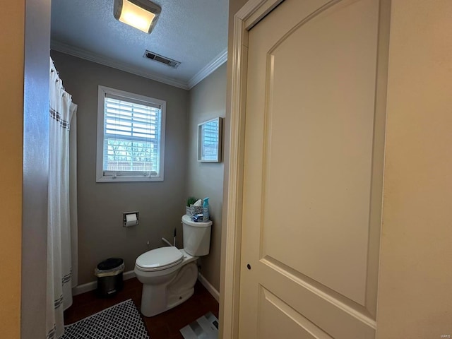 bathroom with toilet, ornamental molding, wood finished floors, a textured ceiling, and baseboards