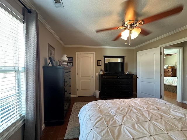 bedroom featuring dark wood-style flooring, ornamental molding, baseboards, ceiling fan, and a textured ceiling