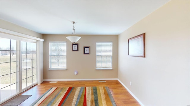 unfurnished dining area with healthy amount of natural light, light wood finished floors, and baseboards