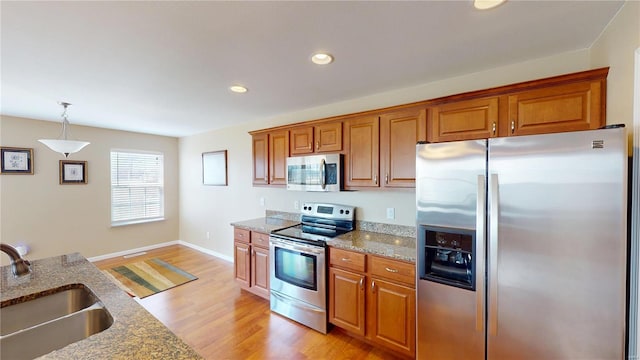 kitchen with stainless steel appliances, a sink, brown cabinetry, and recessed lighting