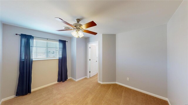 unfurnished room featuring ceiling fan, light carpet, and baseboards