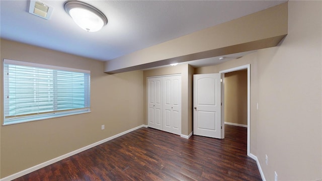 unfurnished bedroom with wood finished floors, baseboards, and a closet