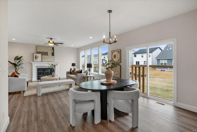 513 Beneficial Way, Saint Charles, MO 63304 - dining area with wood finished floors, a chandelier, baseboards, a ceiling fan, and a glass covered fireplace