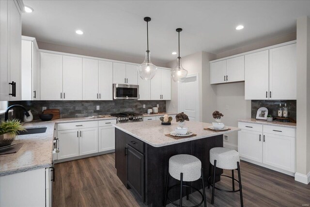 513 Beneficial Way, Saint Charles, MO 63304 - kitchen with stainless steel microwave, a sink, stove, tasteful backsplash, and dark wood finished floors