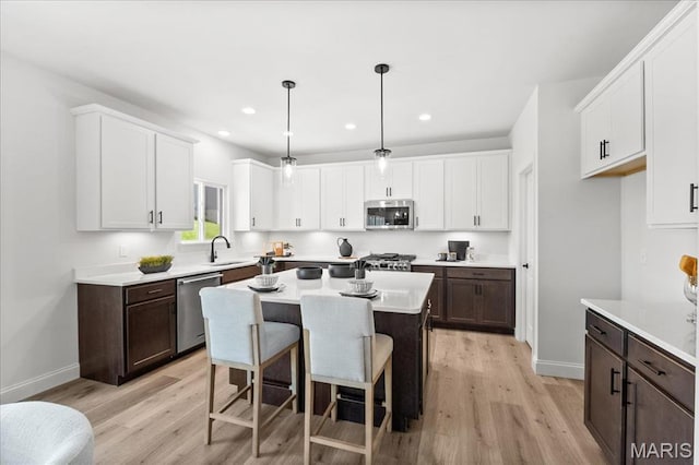 513 Beneficial Way, Saint Charles, MO 63304 - kitchen with stainless steel appliances, a sink, dark brown cabinets, white cabinetry, and light wood finished floors