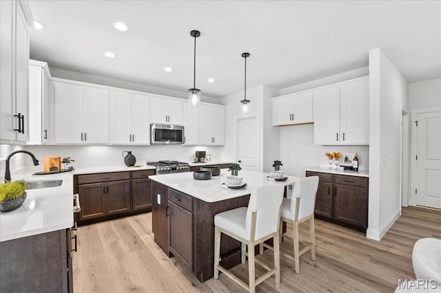 513 Beneficial Way, Saint Charles, MO 63304 - kitchen featuring appliances with stainless steel finishes, dark brown cabinets, light wood-style flooring, a sink, and recessed lighting