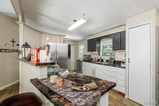 2 S Circle Dr, Carlyle, IL 62231 - kitchen featuring dark countertops, freestanding refrigerator, light wood-style floors, a peninsula, and vaulted ceiling